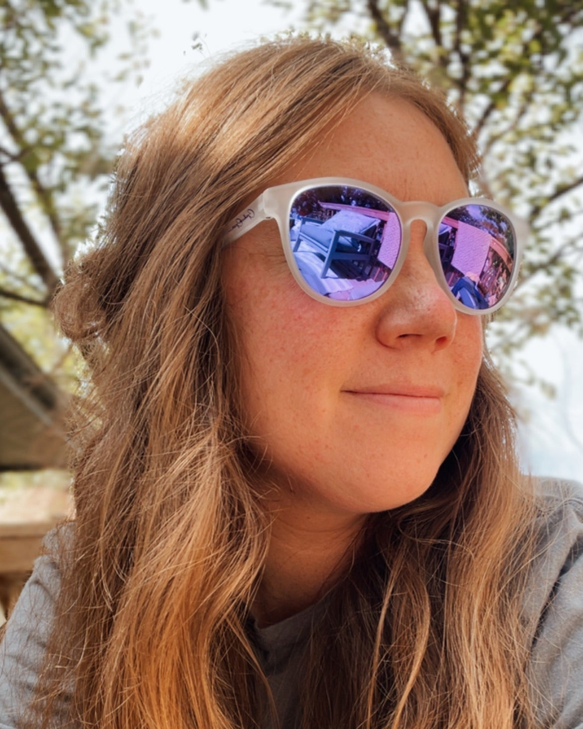 Woman wearing sunglasses with purple mirror lenses.