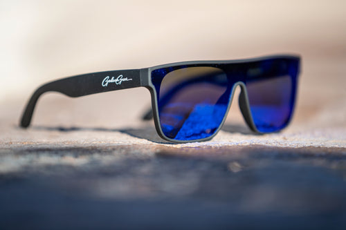 Sunglasses with blue lenses and black frame on a textured surface
