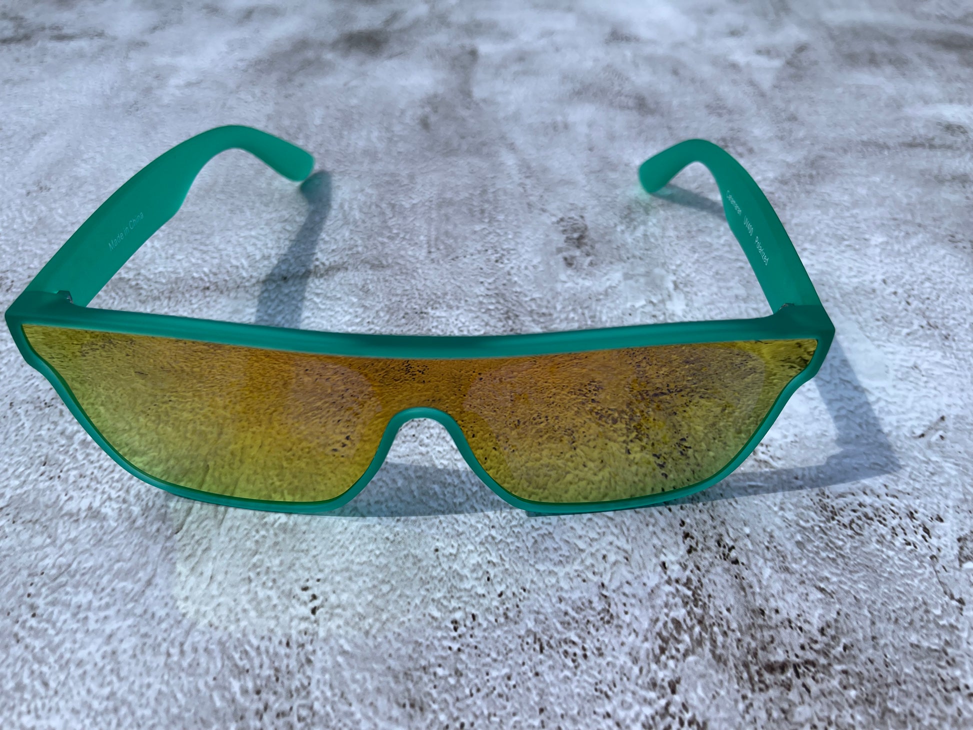 A slightly transparent seafoam green frame with lenses that reflect back golden and orange.
