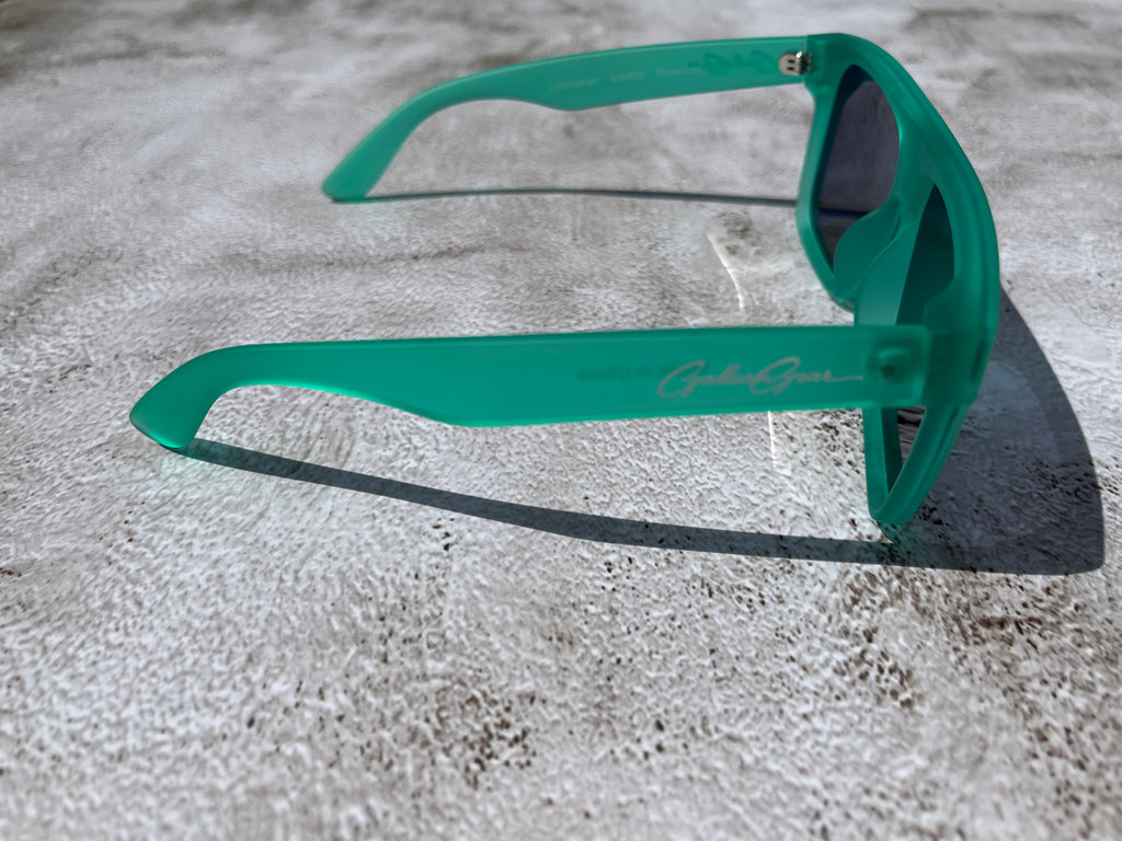 Slightly transparent bright seafoam green sunglasses on a textured surface