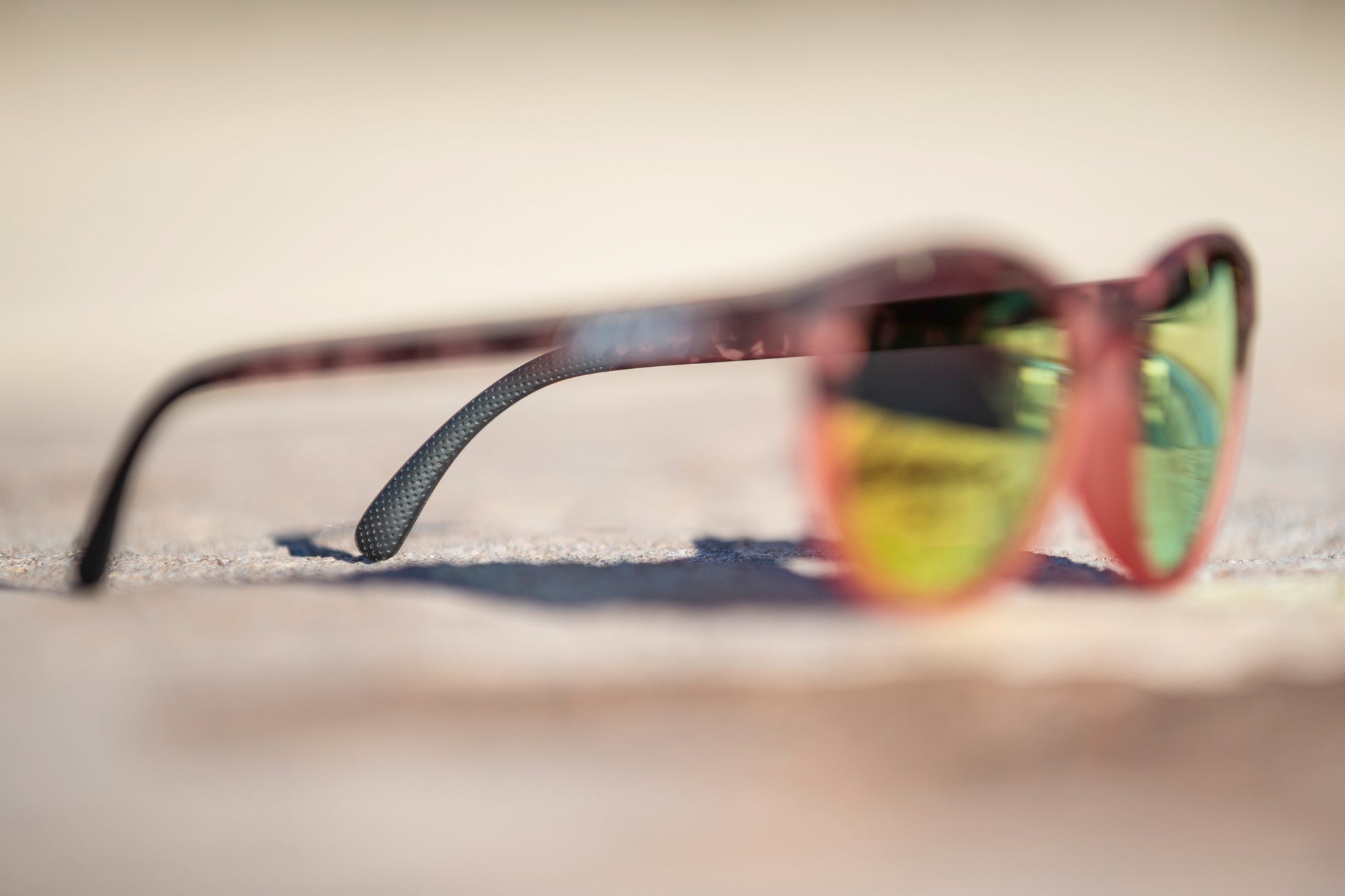 Blurred sunglasses with a blurred background with a focus on the black grip on the end of the sunglass's leg.