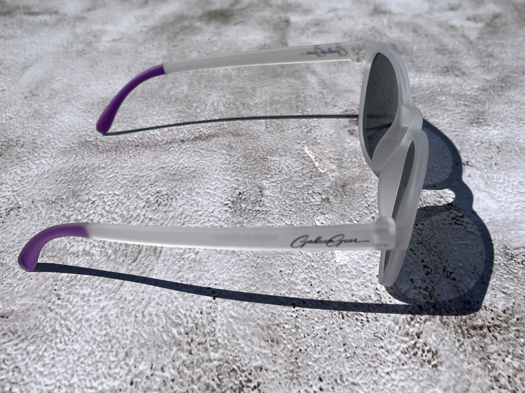 Sunglasses with purple temple grips on a textured surface