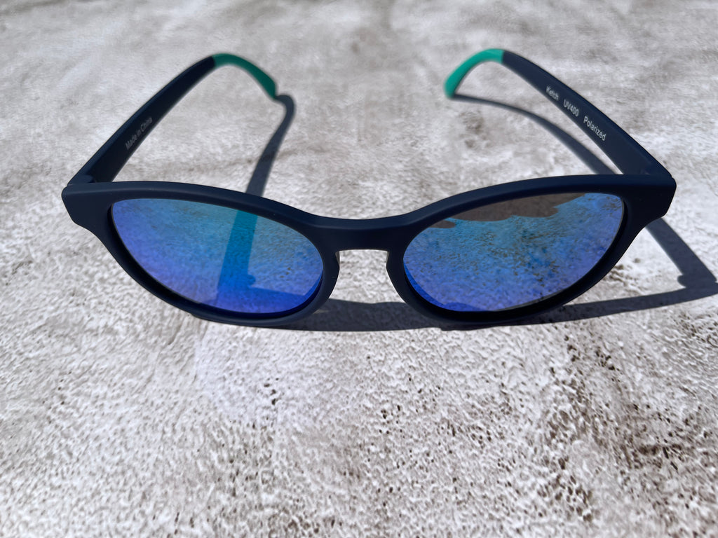 Navy blue sunglasses with blue lenses on a textured surface