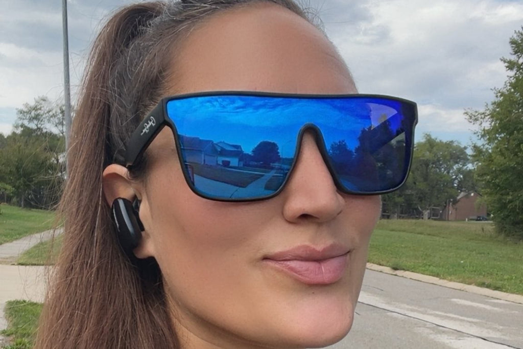 Woman wearing blue reflective sunglasses outdoors on a cloudy day