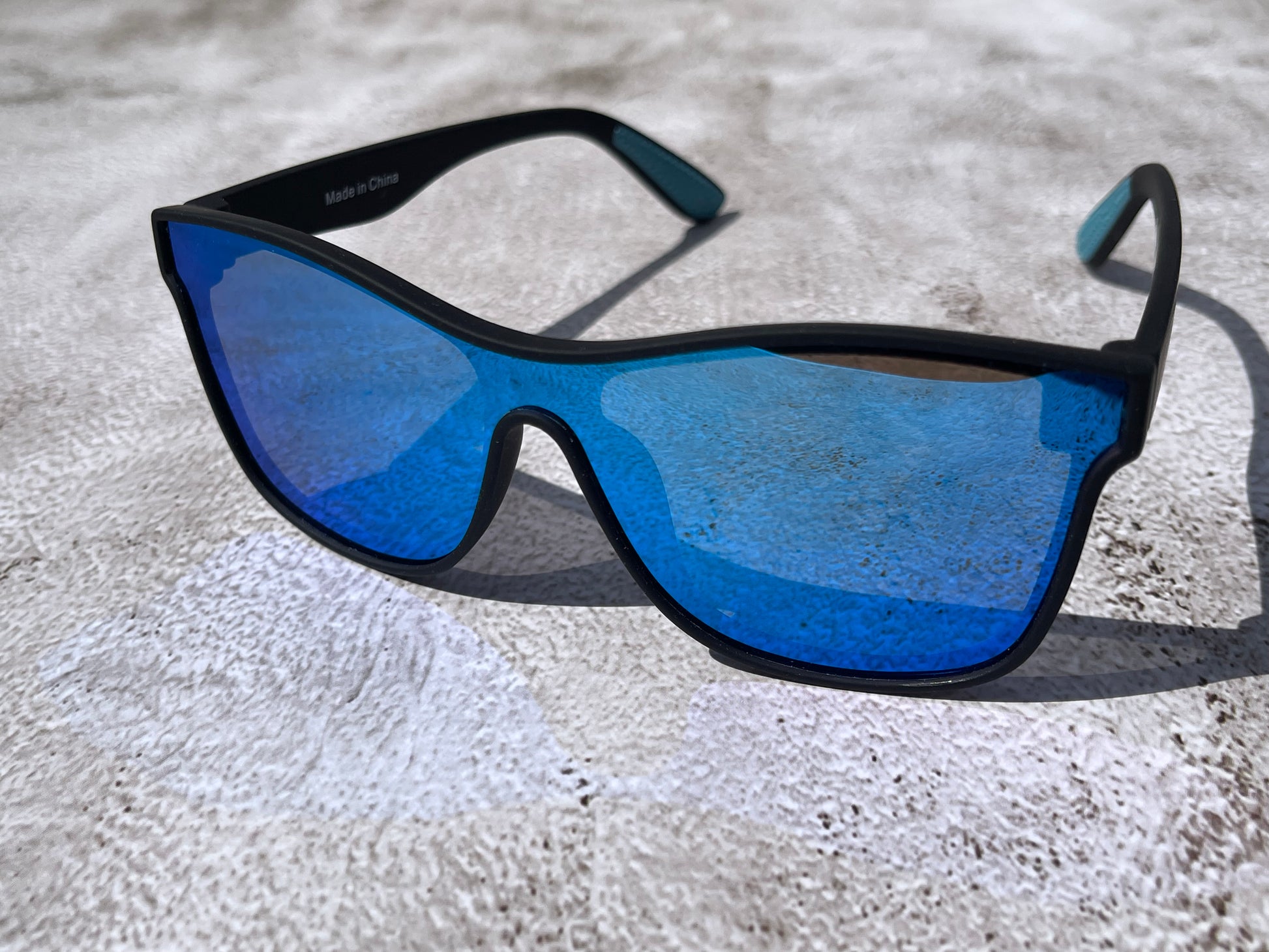 Sunglasses with blue lenses and black frames on a textured surface