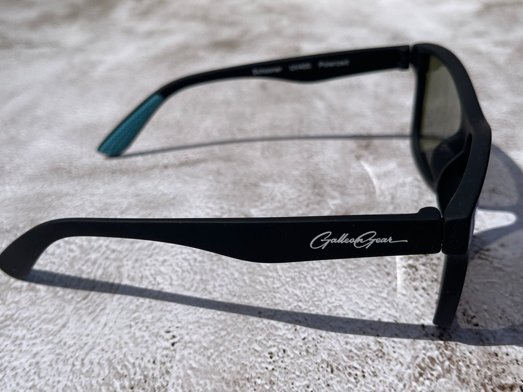 Black sunglasses with Galleon Gear branding on a light gray textured surface.