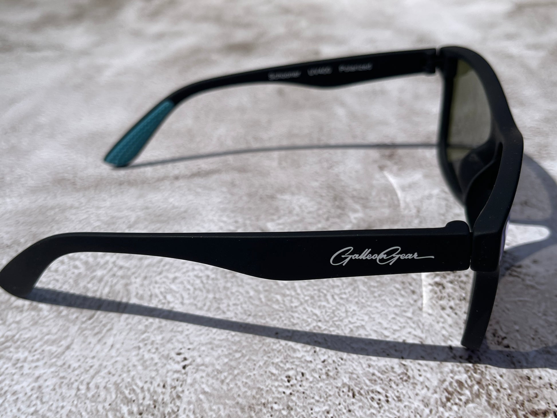Black sunglasses with Galleon Gear branding on a light gray textured surface.