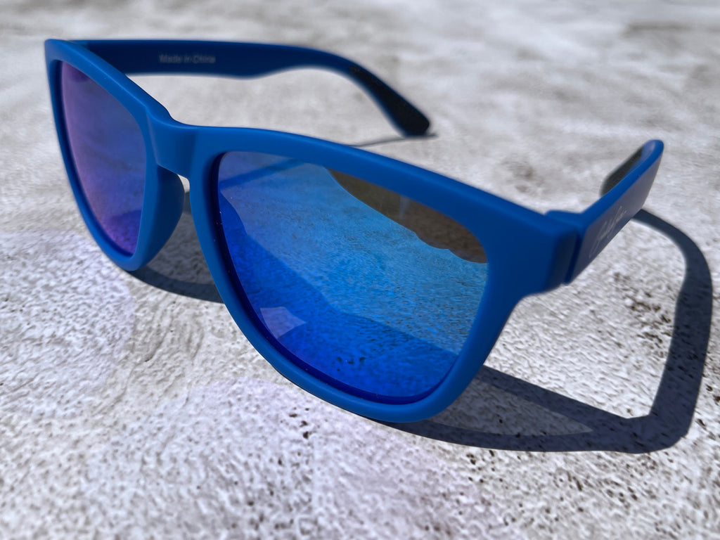 Blue sunglasses with blue reflective lenses on a textured surface.