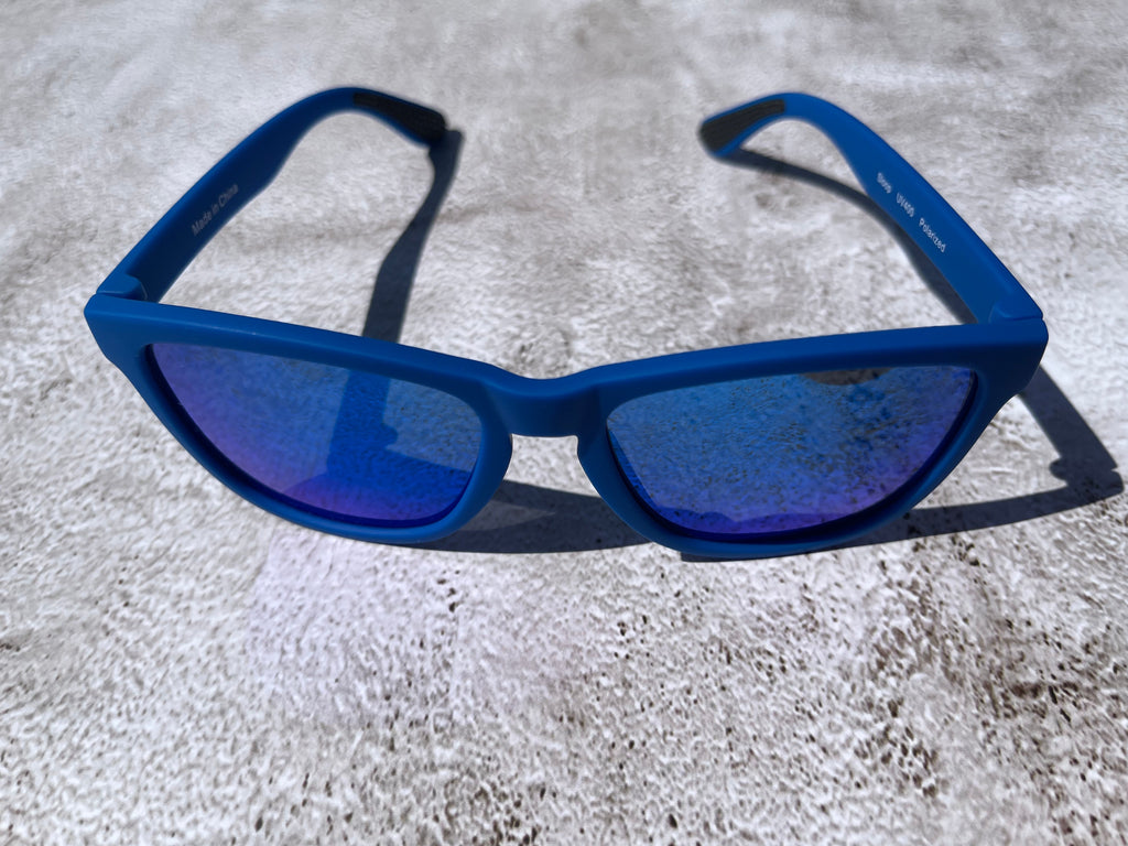 Blue sunglasses with blue reflective lenses on a textured surface.