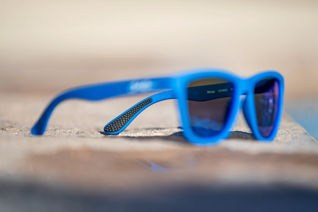 Blurred sunglasses showing the detail of the black temple grip with a blurred background and surface.