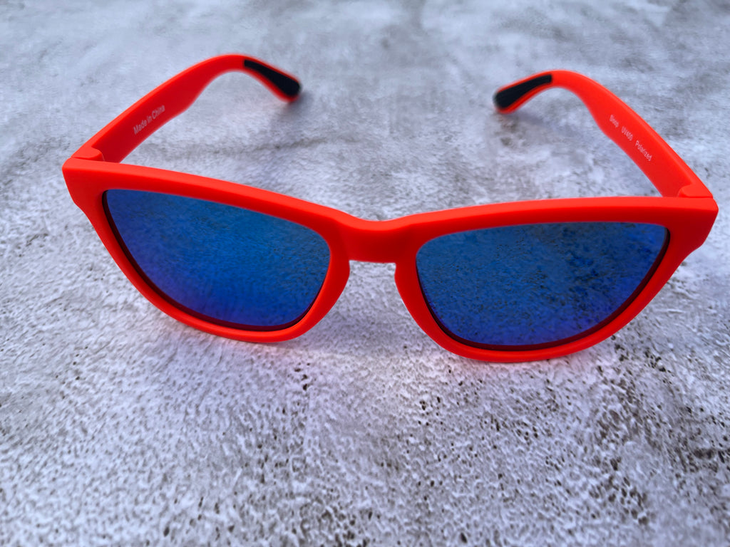 Bright orange sunglasses with blue lenses on a textured gray surface