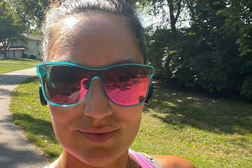 Woman wearing pink sunglasses and a tank top outdoors