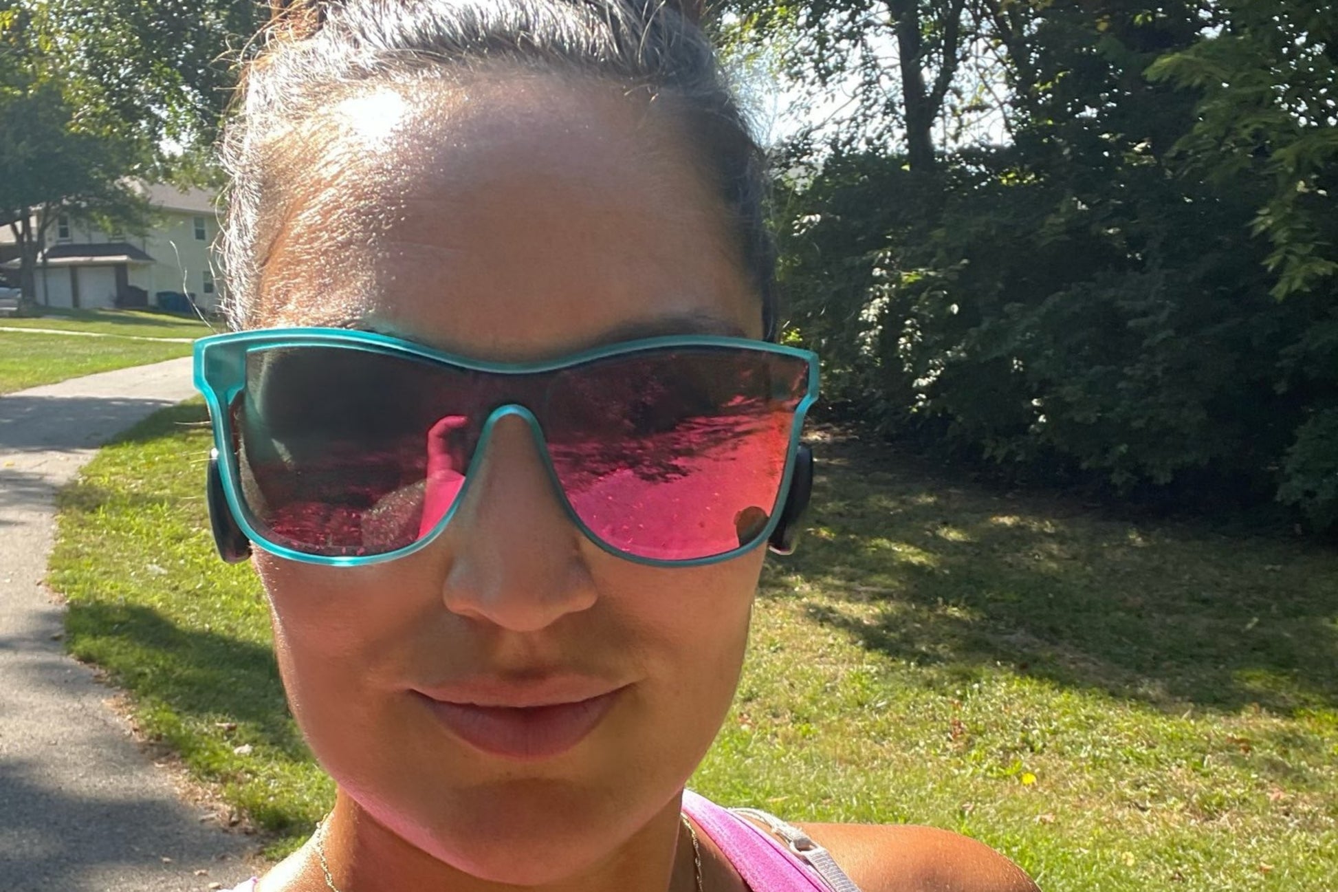 Woman wearing pink sunglasses and a tank top outdoors